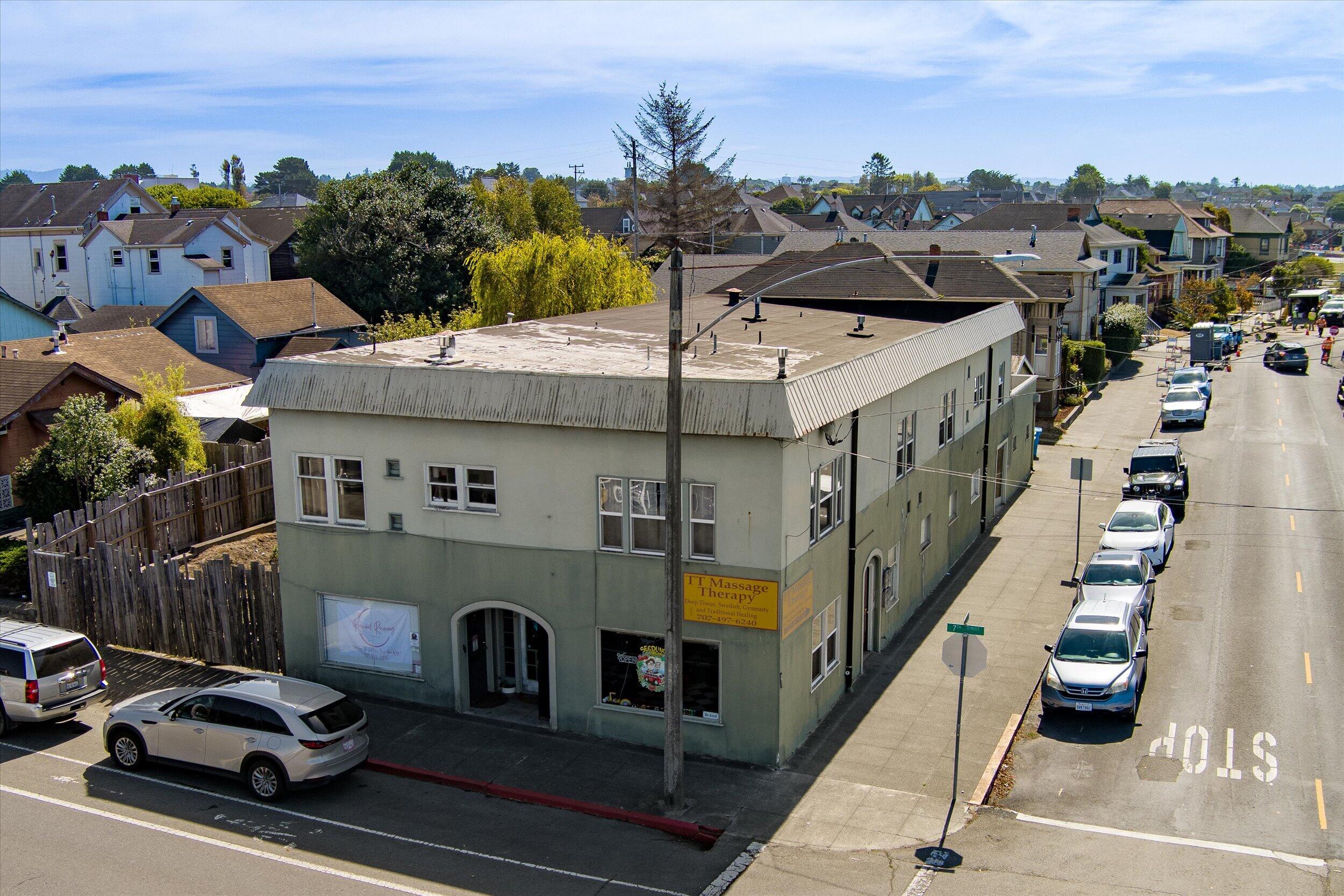 Two-story corner commercial building with a pale green facade and massage therapy storefront.