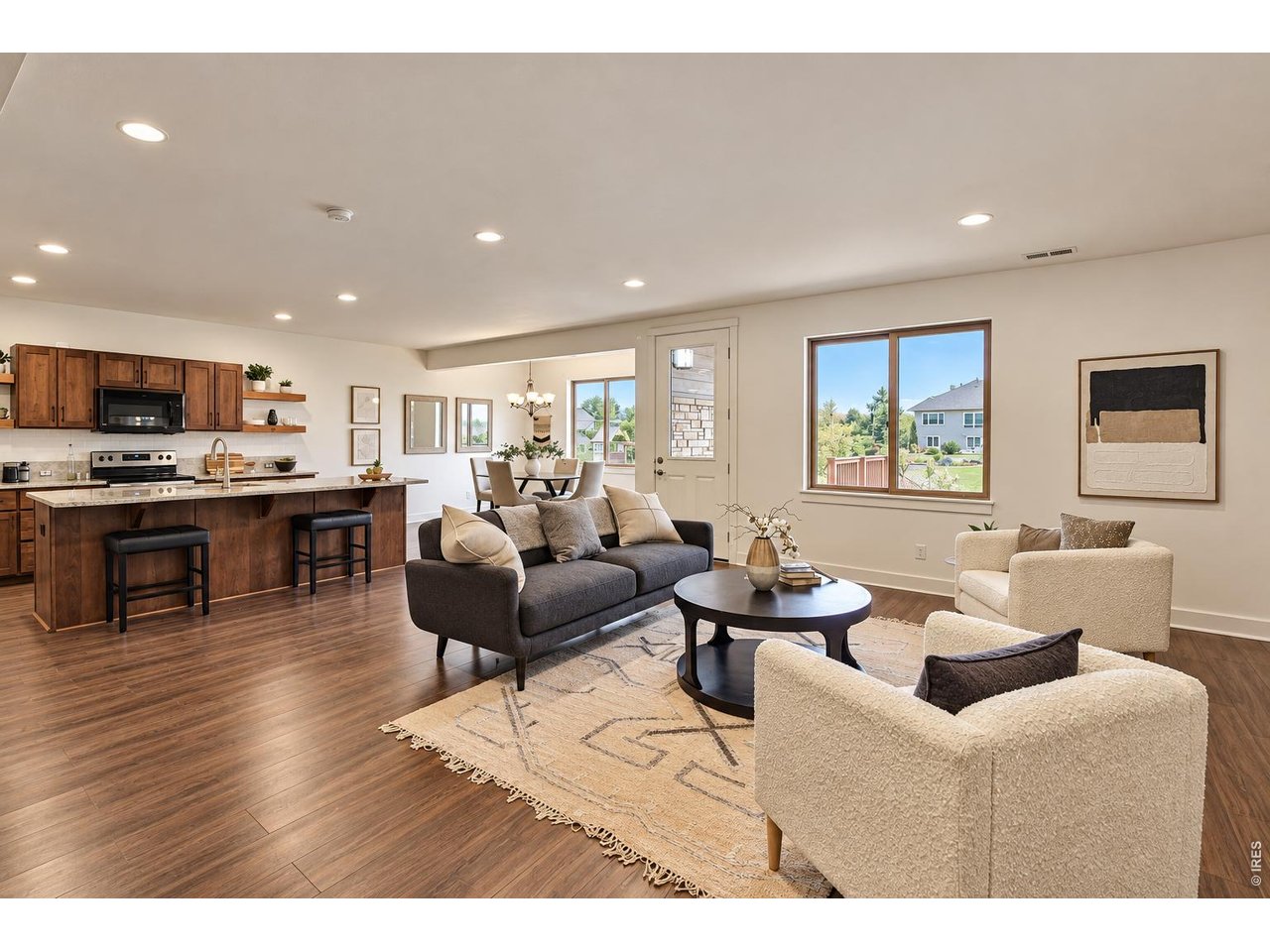 Open-plan living room and kitchen with a dark wood island and large windows.