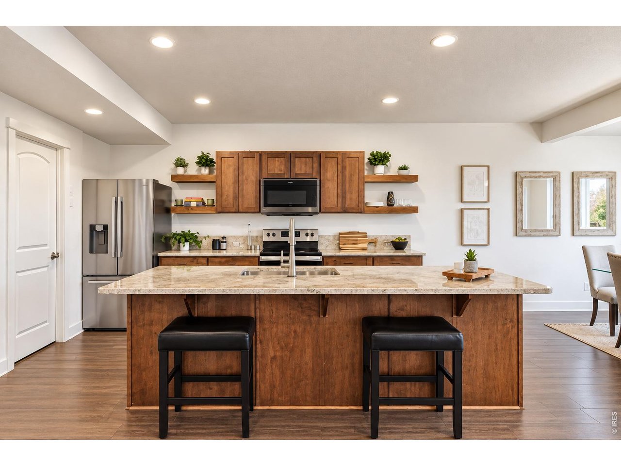 Kitchen with warm wood cabinets, stainless steel appliances, and a large island with two stools.