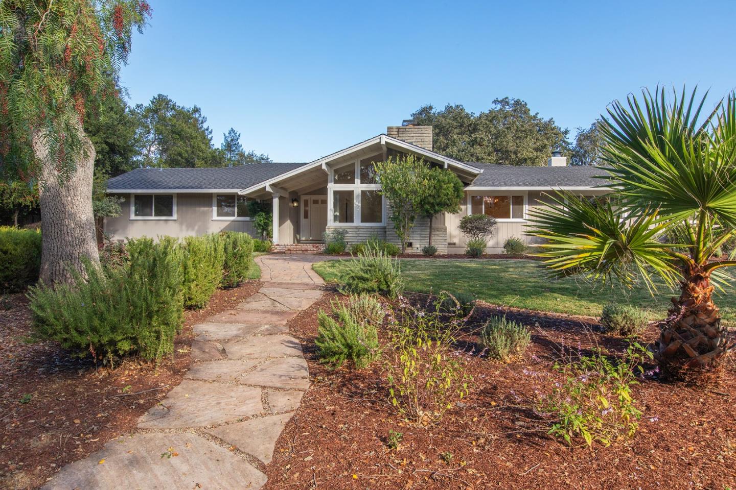 Single-story home with a gabled entrance, stone walkway, and landscaped front garden.