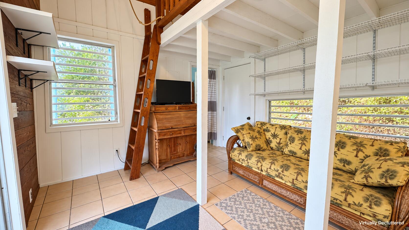 Furnished interior with a tropical-print sofa, wire shelving, louvered windows, and a wooden ladder.