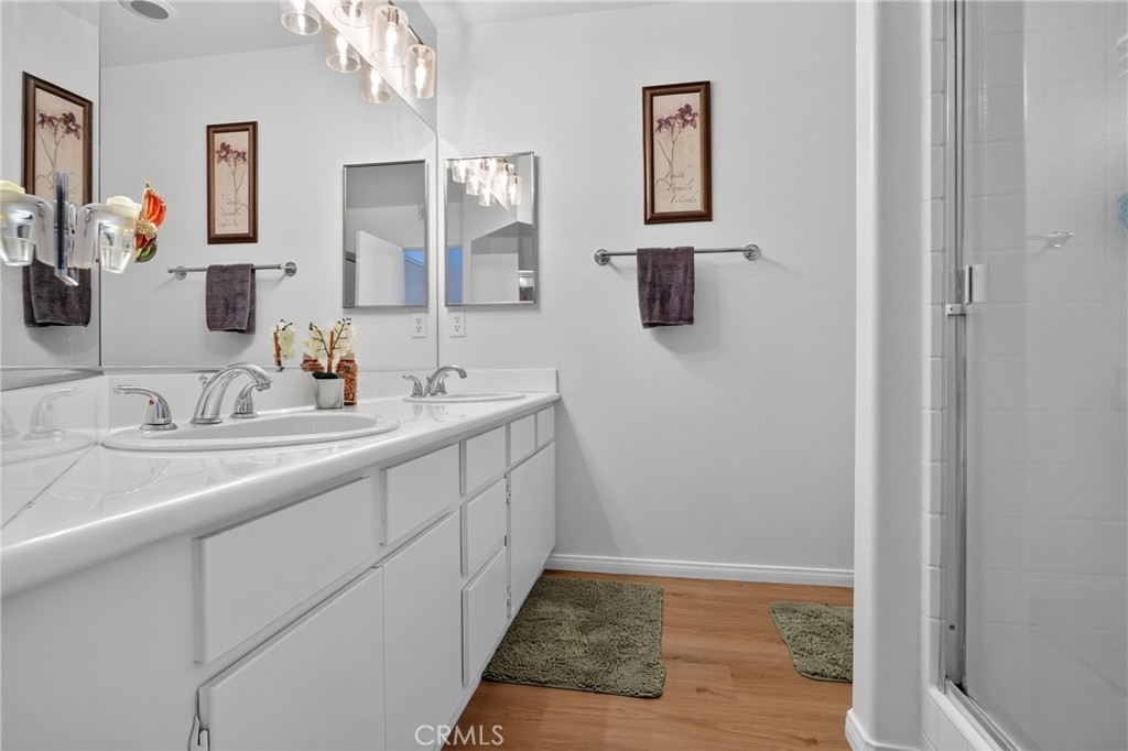 Bathroom with a double-sink vanity, wall mirrors, and a glass-enclosed shower.