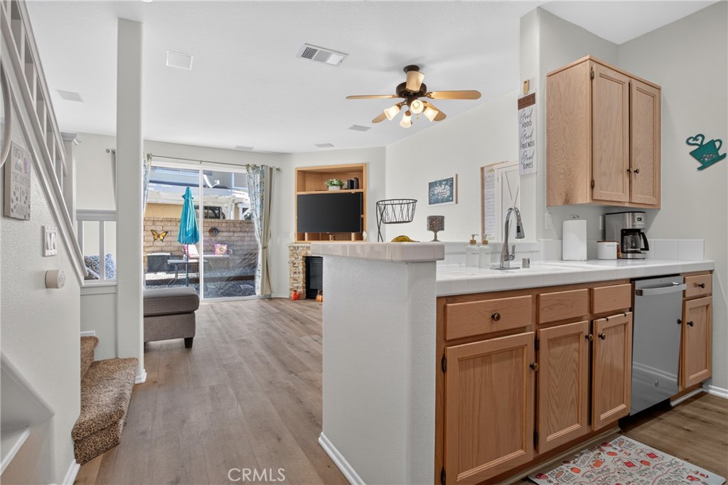 Kitchen with oak cabinets and a peninsula opening onto a living area with sliding glass doors.