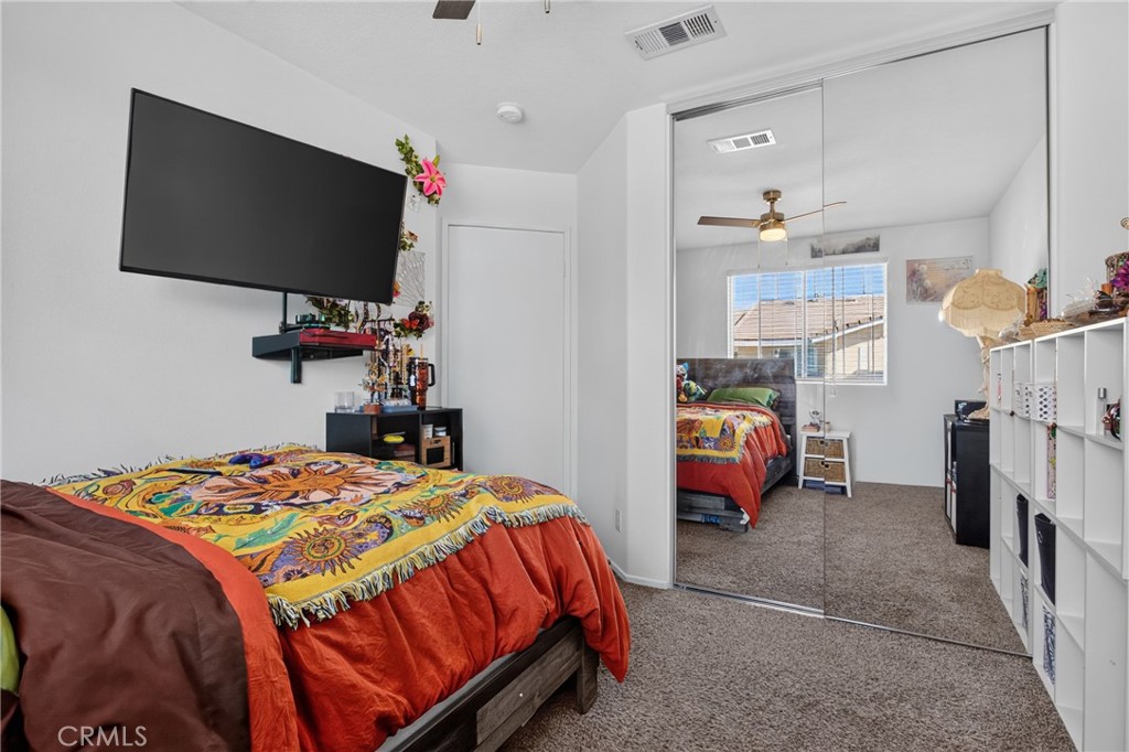 Bedroom with colorful bedding, a wall-mounted television, and mirrored closet doors.