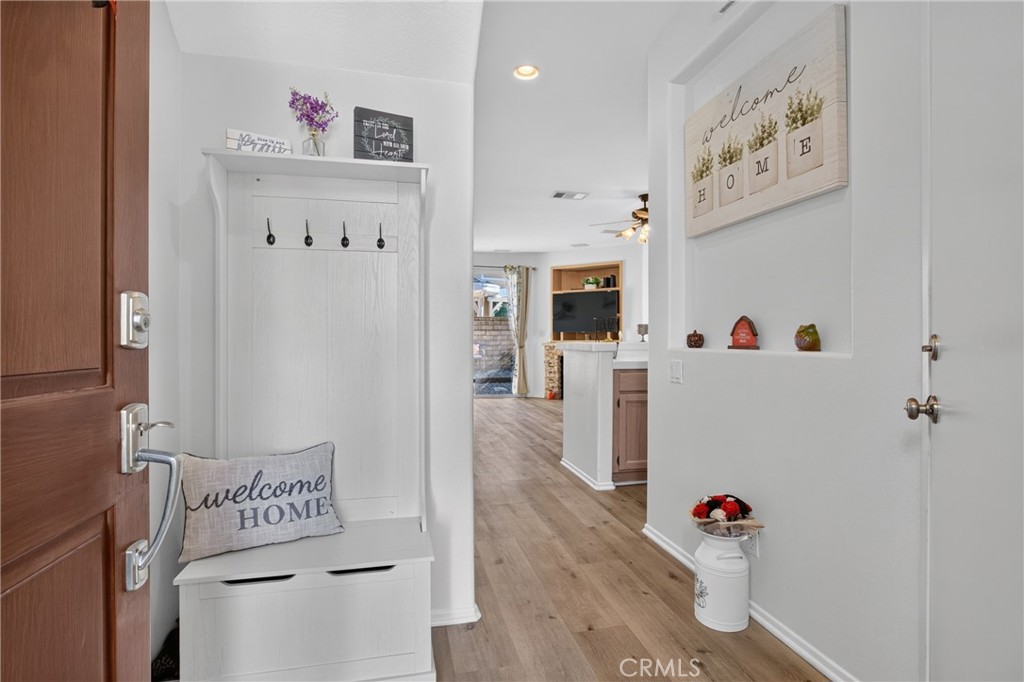 Entryway with a white coat-hook bench, wood flooring, and a view into the living area.