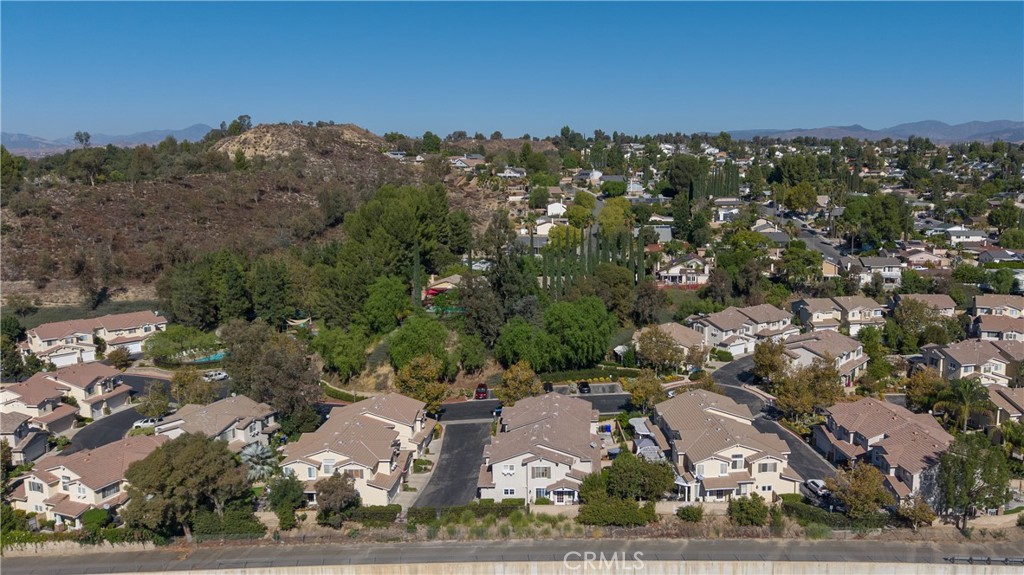 Aerial view of Rock Creek homes beside a wooded hillside, with distant mountains.