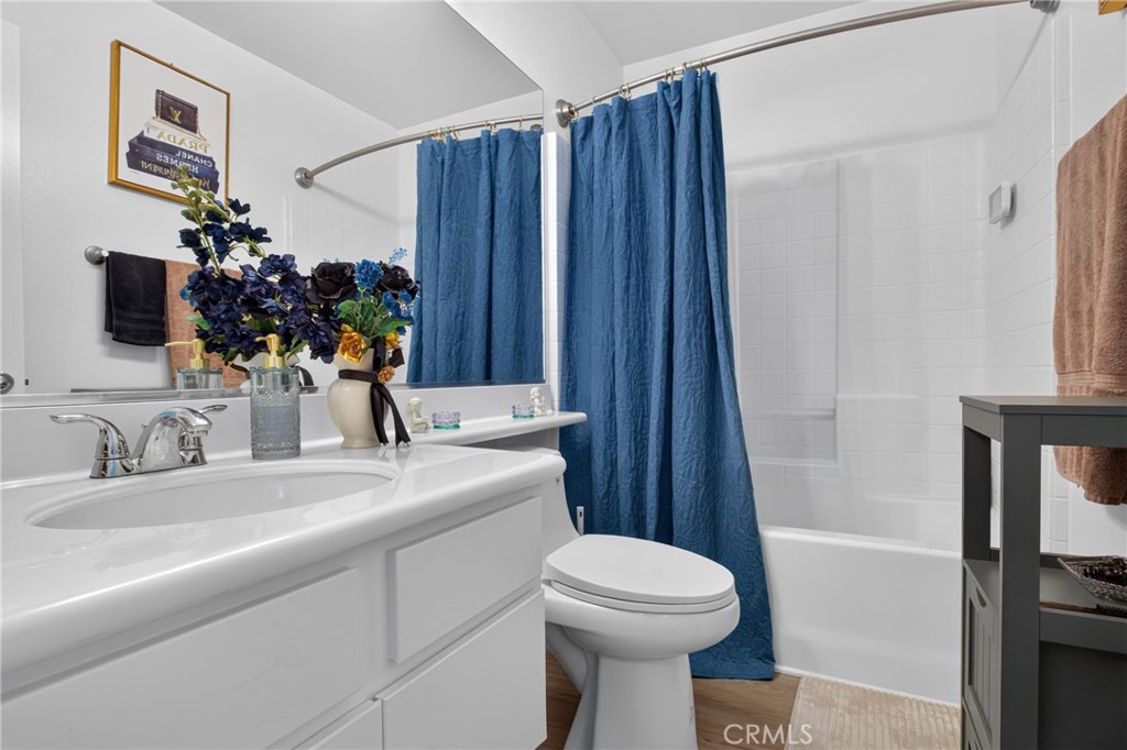 Bathroom with a white vanity, toilet, and bathtub behind a blue shower curtain.