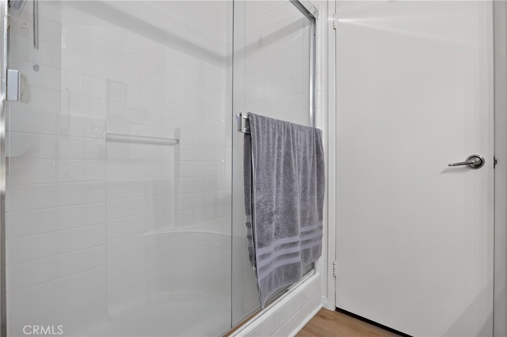 Bathroom with a glass shower enclosure, white tile, and a gray towel.