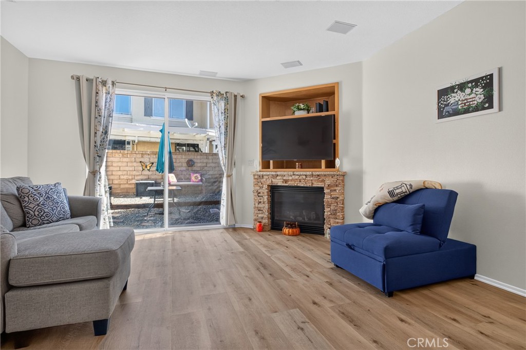 Living room with a stone fireplace, built-in television, and sliding glass doors to a patio.