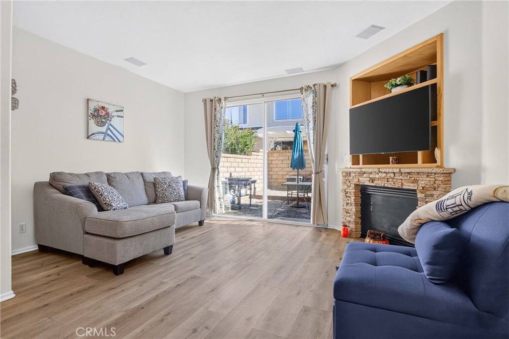 Living room with gray and blue sofas, a stone fireplace, and sliding doors to the patio.