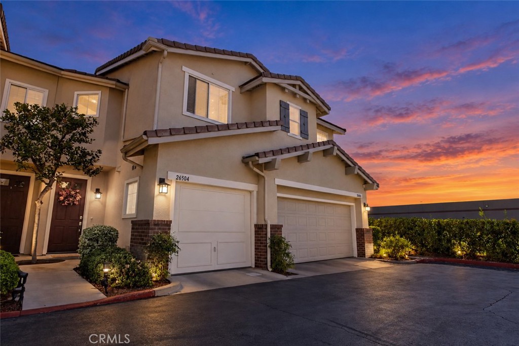 Two-story home with twin garages beneath a vivid sunset sky.