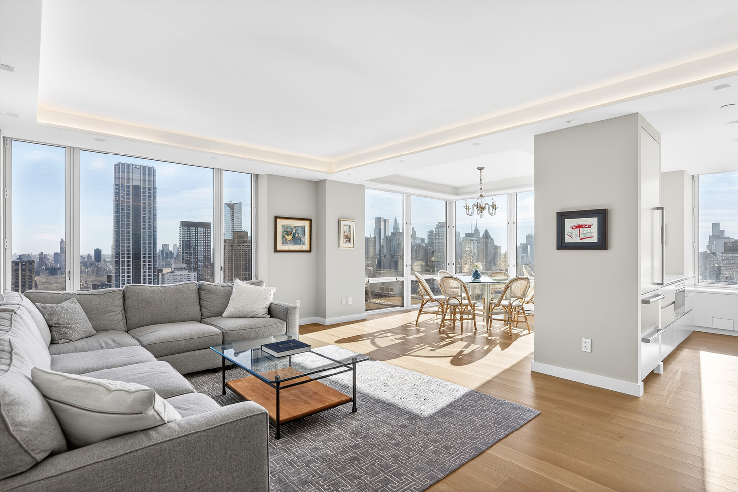 Open-plan living and dining room with floor-to-ceiling windows overlooking the city skyline.