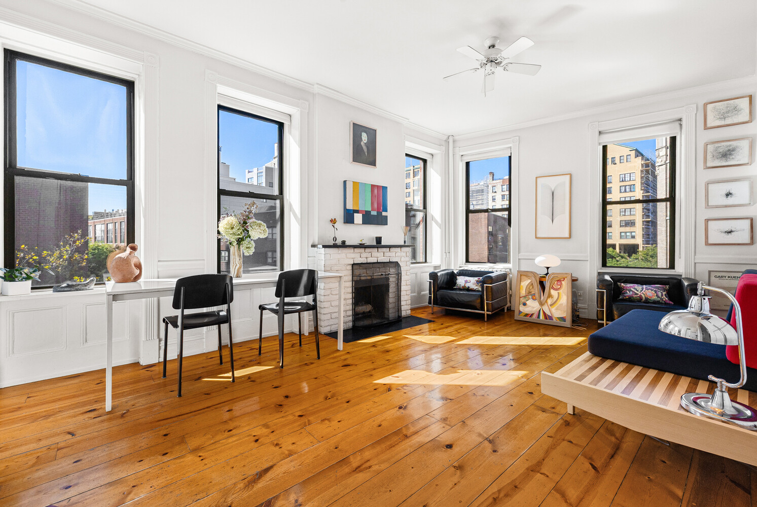 Living room with a white brick fireplace, tall windows, and warm wood floors.