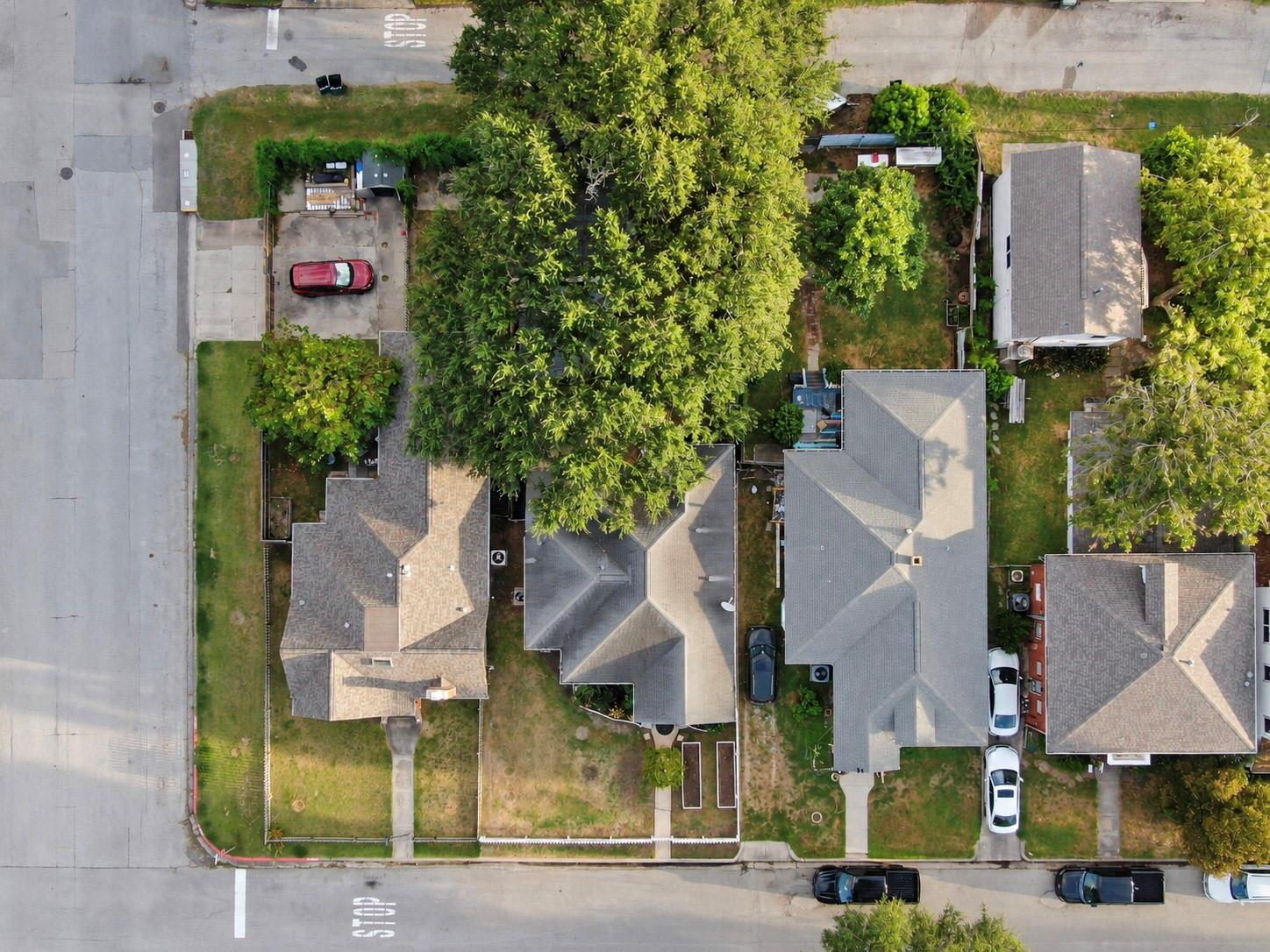 Aerial view of a residential property and neighboring homes, with mature trees, yards, and intersecting streets.