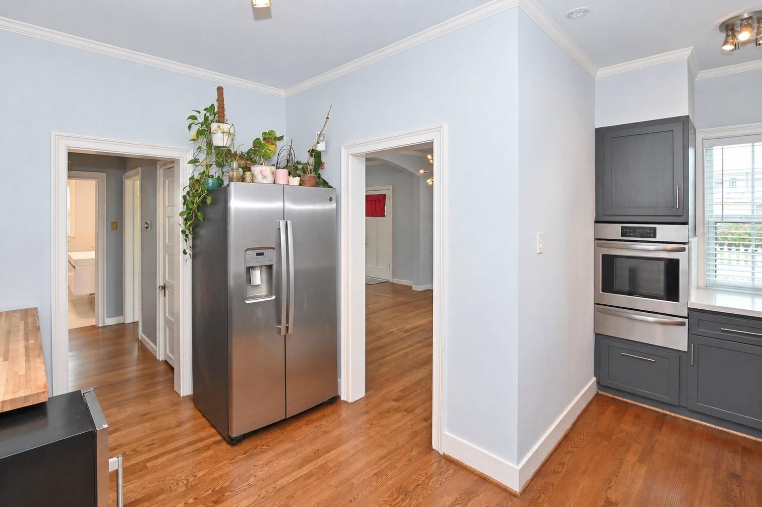 Kitchen with hardwood floors, stainless steel refrigerator, and dark gray cabinets with a built-in oven.
