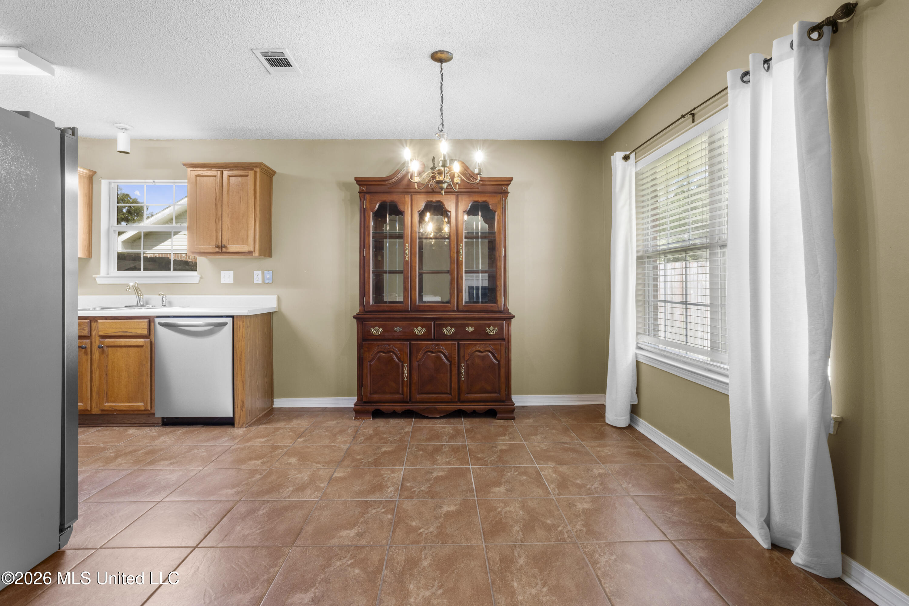 Kitchen and dining area with terracotta tile, wood cabinets, and a large china cabinet.