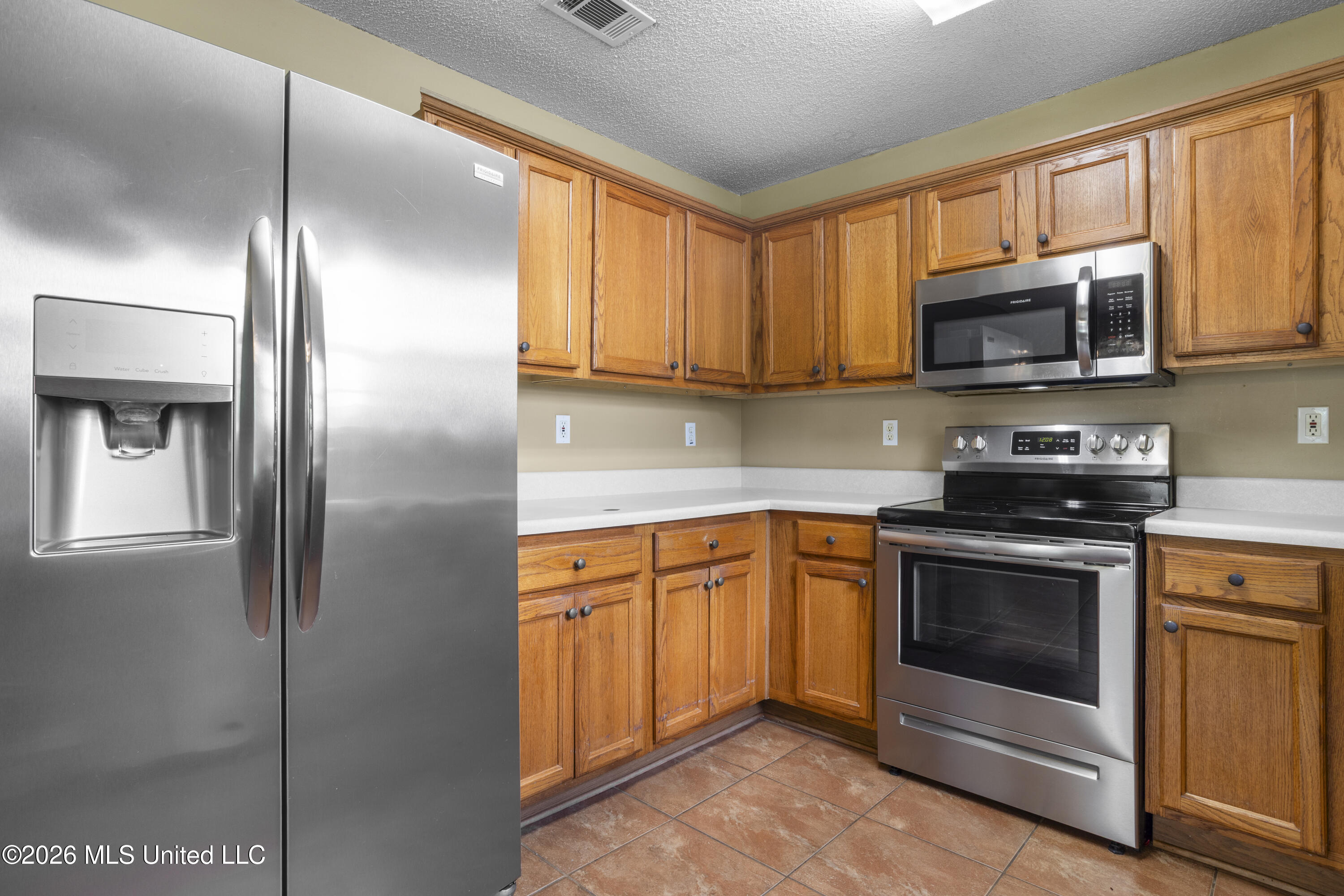 Kitchen with wood cabinets, white countertops, and stainless steel appliances.