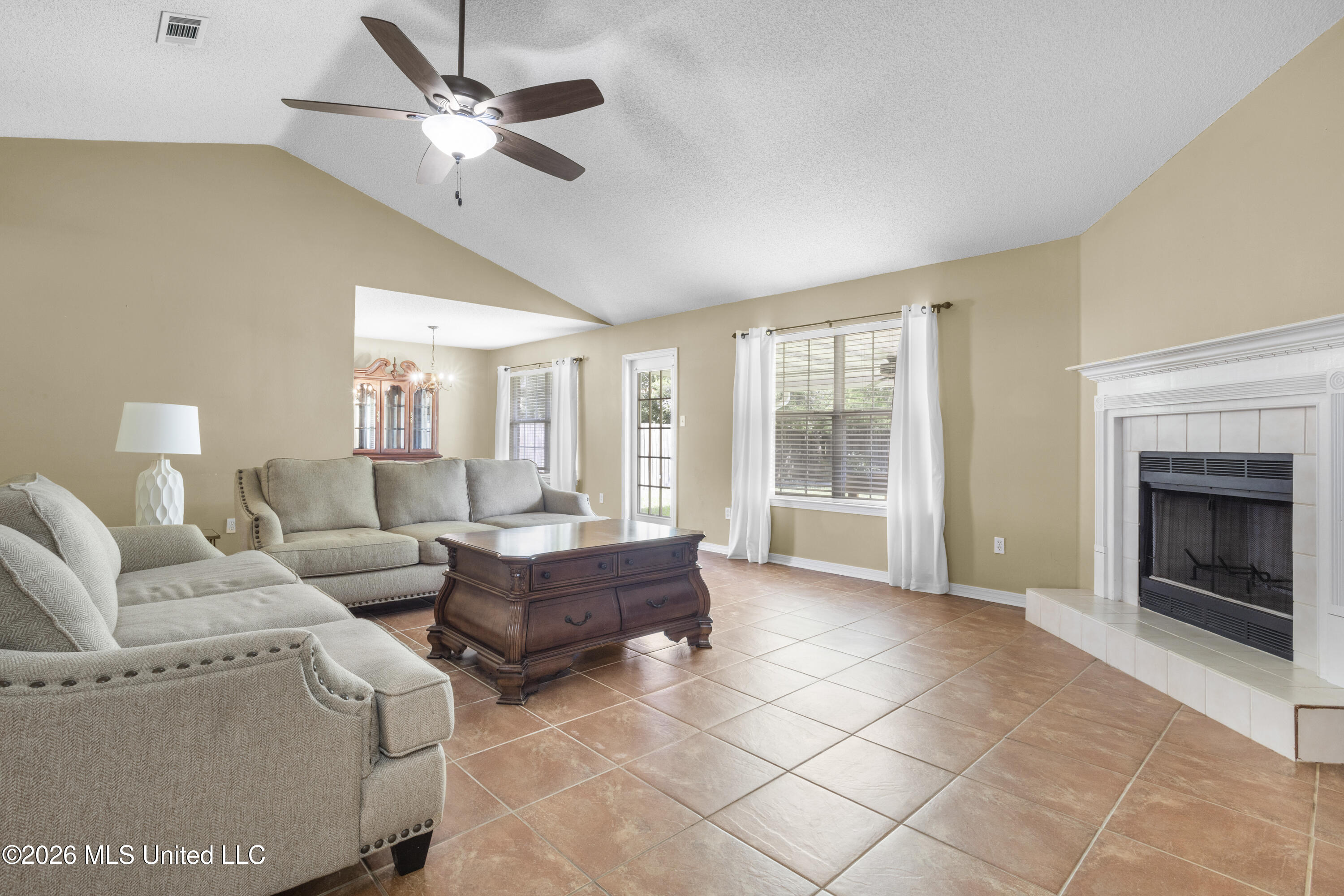 Furnished living room with terracotta tile floors, gray sofas, and a white fireplace.