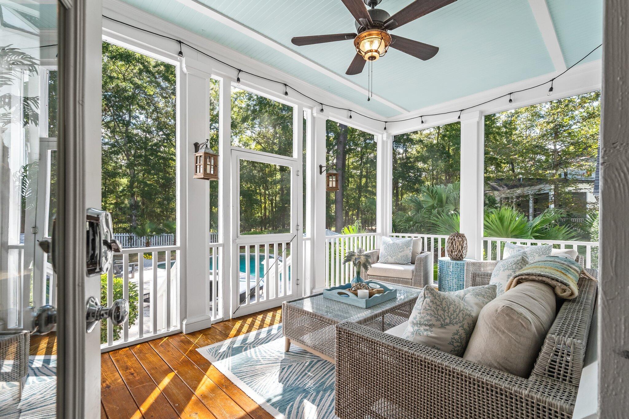 Screened porch with wicker seating, a pale blue ceiling, and a pool visible beyond the railing.