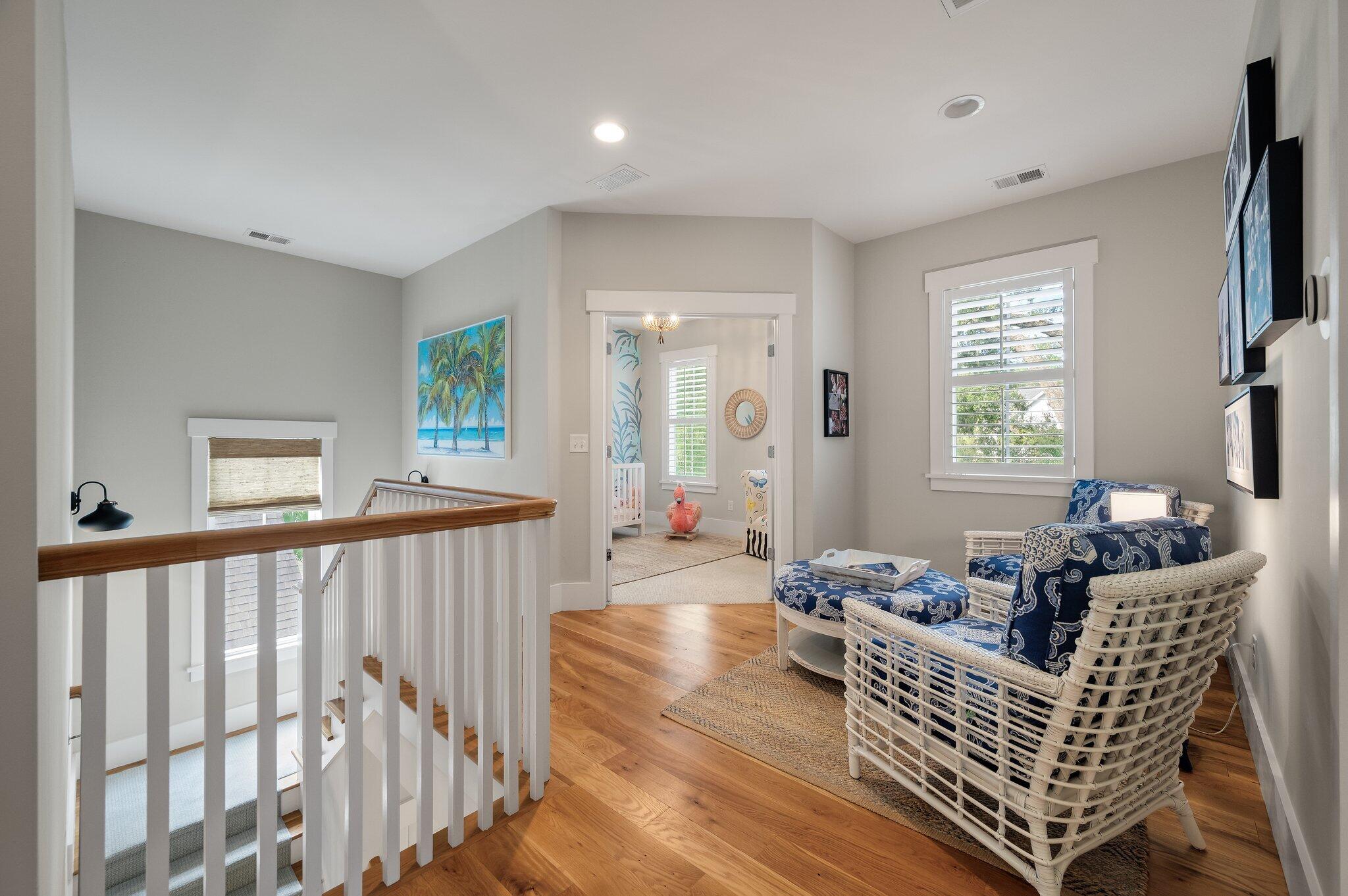 Upstairs landing with blue-and-white wicker seating and a view into a nursery.