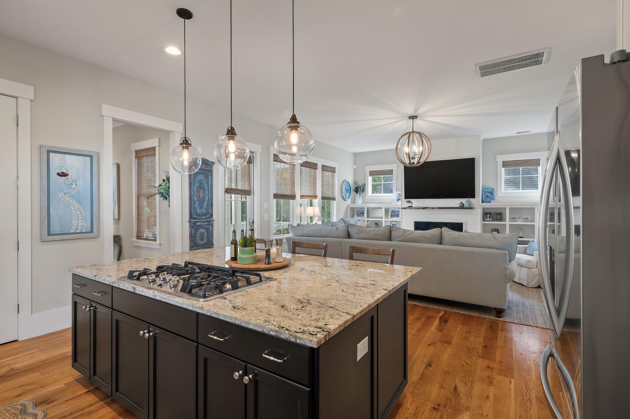 Open kitchen and living room with granite island, gas cooktop, and fireplace.