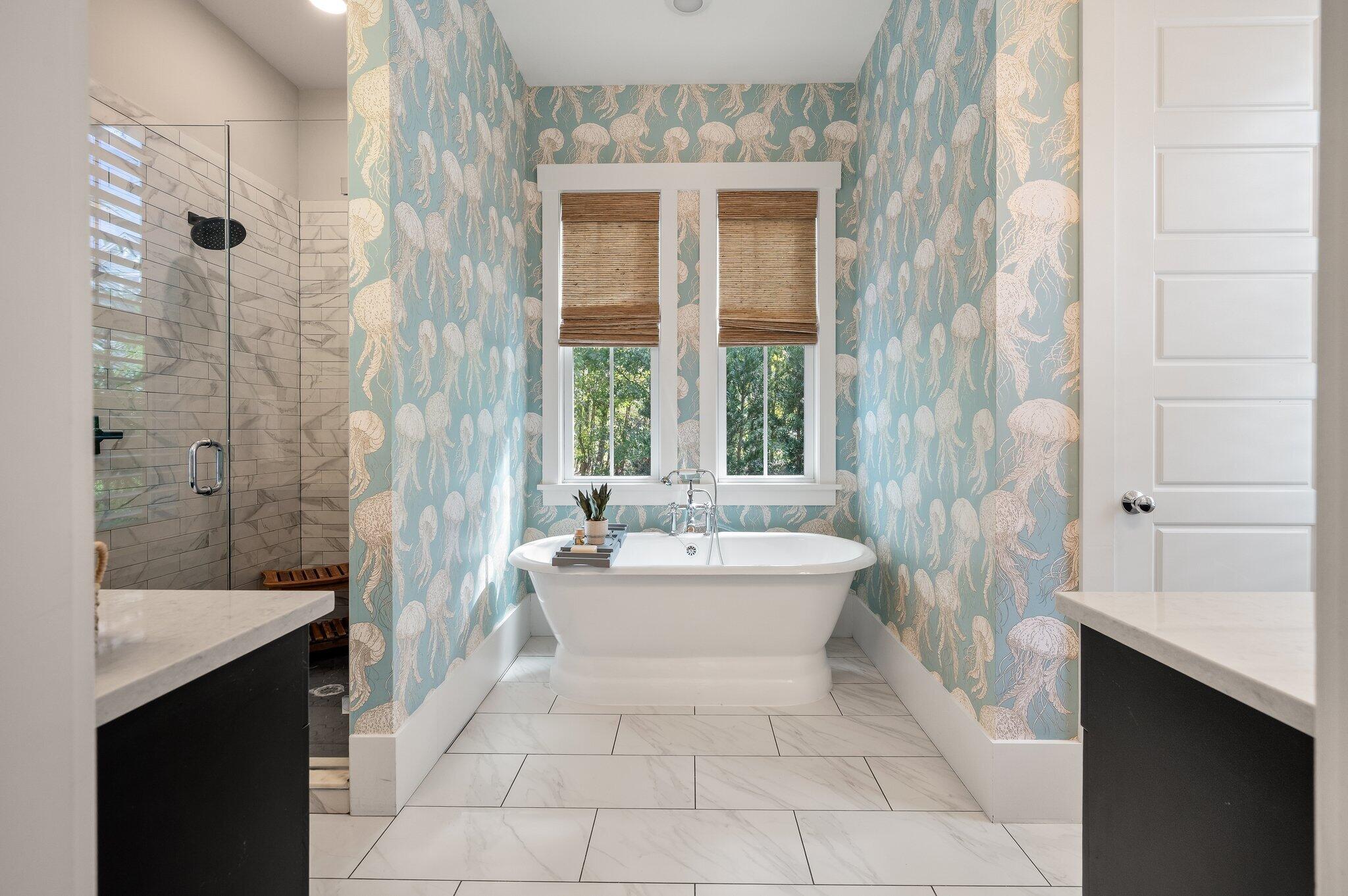 Bathroom with freestanding tub, blue jellyfish wallpaper, and glass shower.