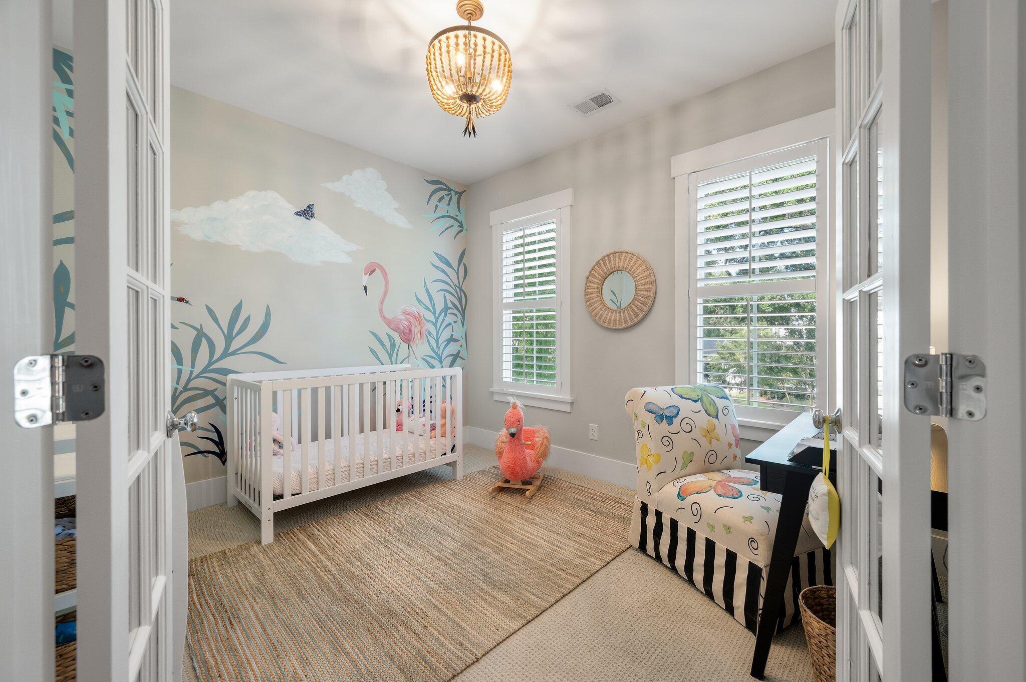 Nursery with a white crib, flamingo mural, shuttered windows, and patterned armchair.