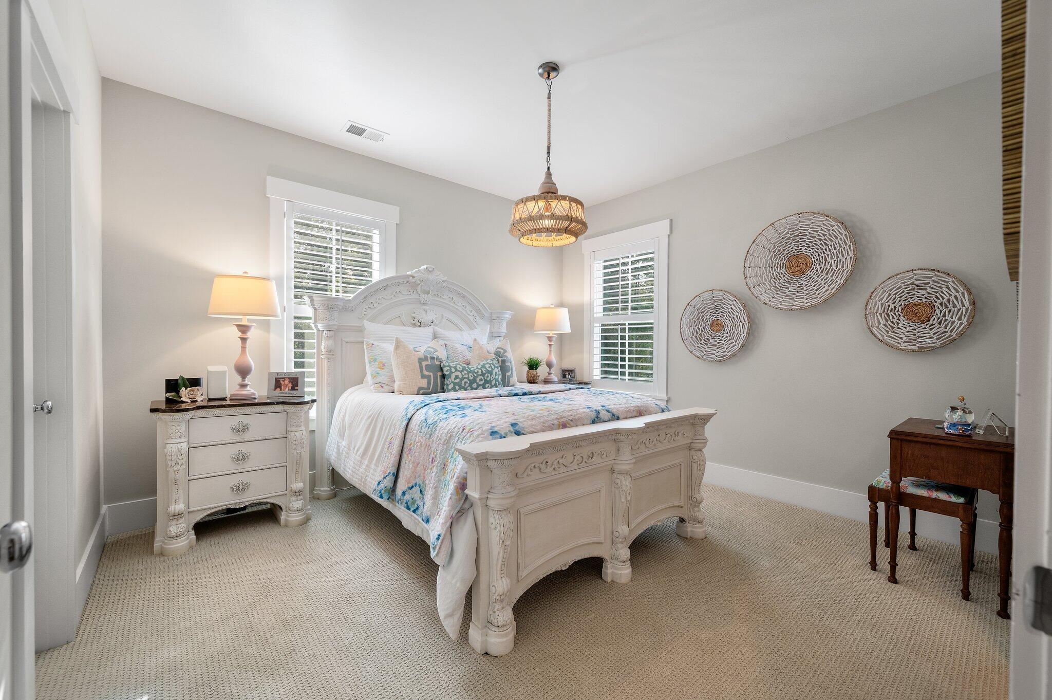 Bedroom with an ornate white carved bed, blue-and-white bedding, and woven baskets on the wall.