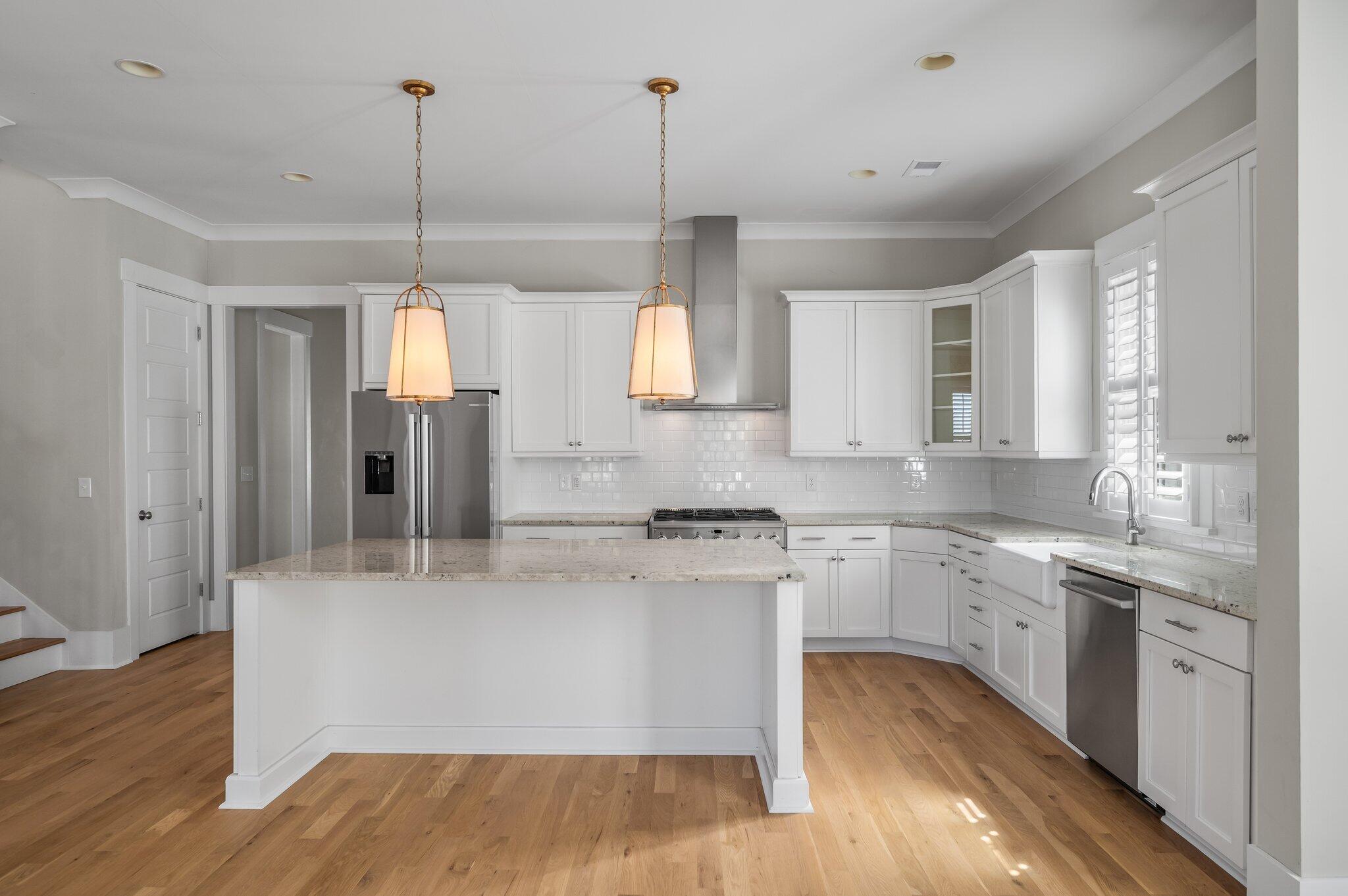Bright kitchen with white cabinets, a large island, and stainless steel appliances.
