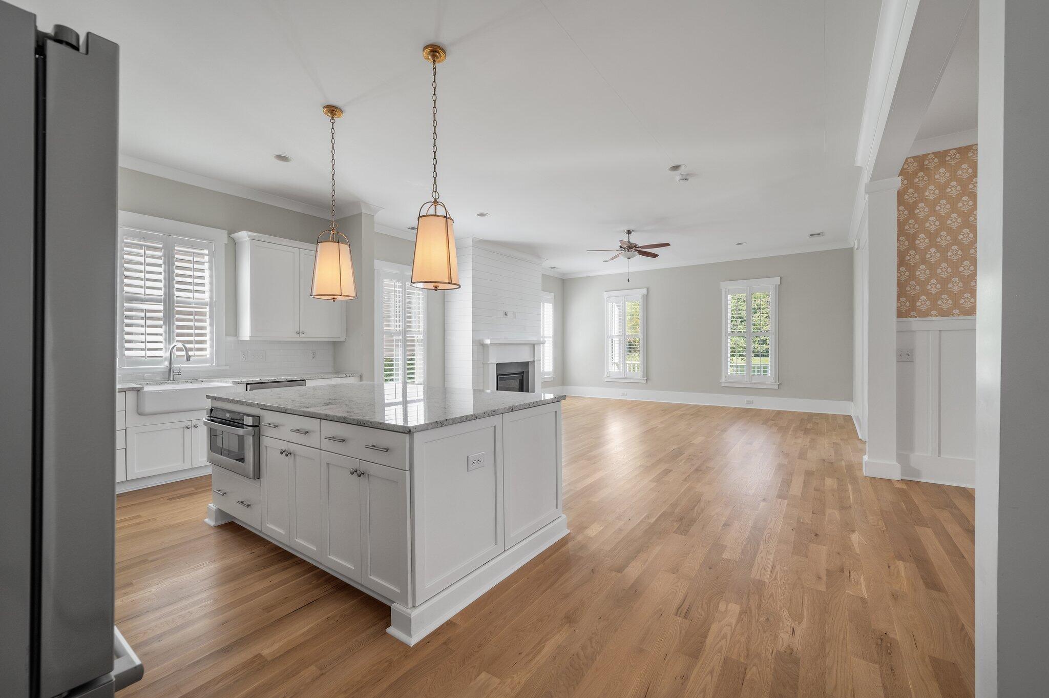 Open kitchen and living area with a large island, wood floors, and fireplace.