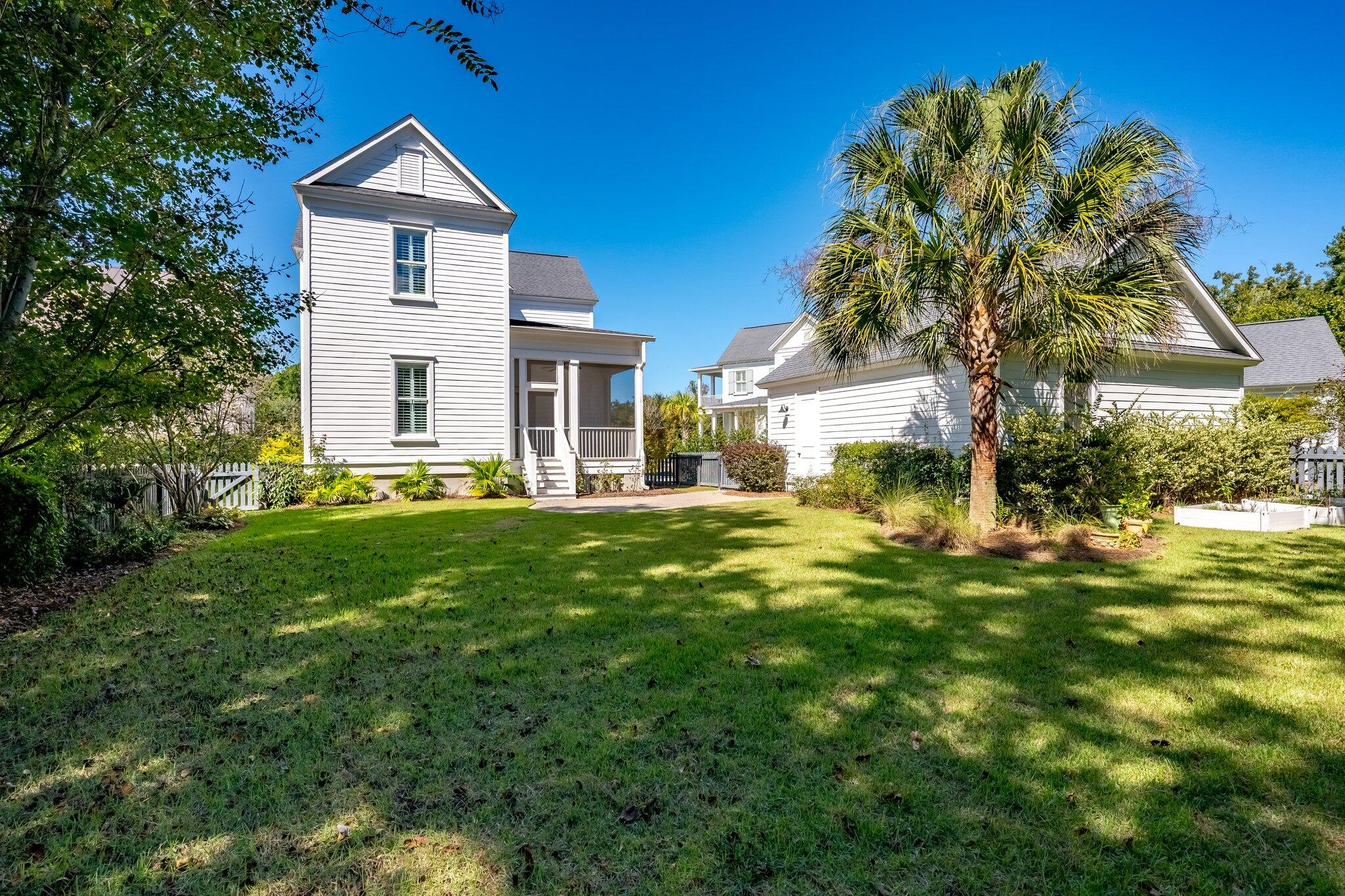 White-sided home with a covered porch, palm tree, and broad backyard lawn.