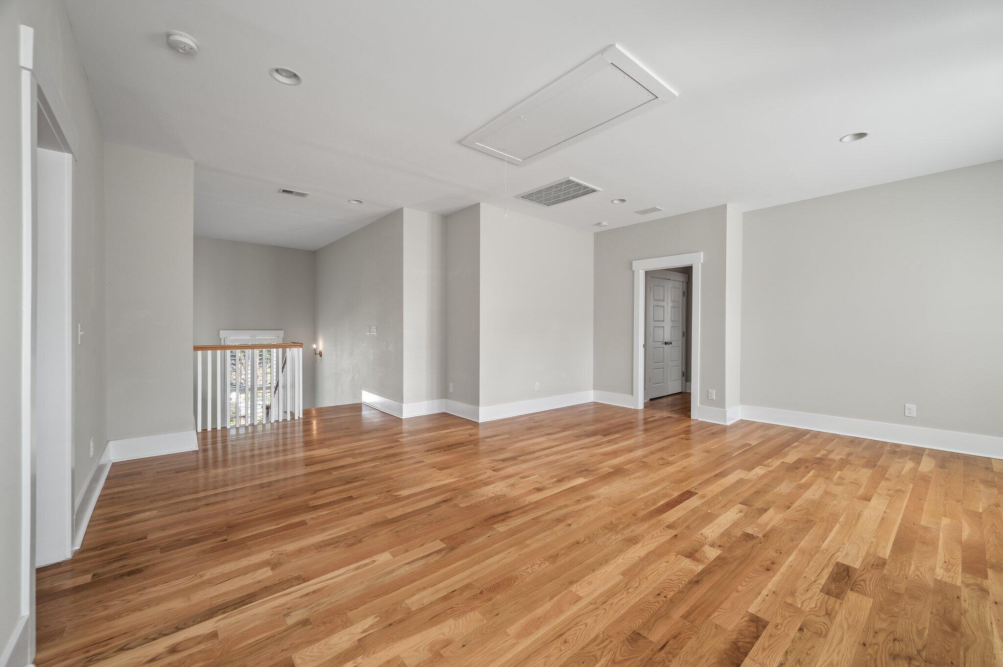Empty upstairs room with hardwood floors and a railing overlooking the stairwell.