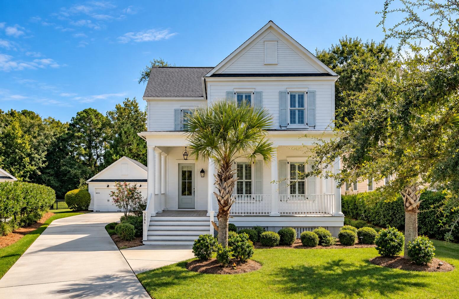 White two-story home with a front porch, pale blue shutters, palm trees, and attached garage.
