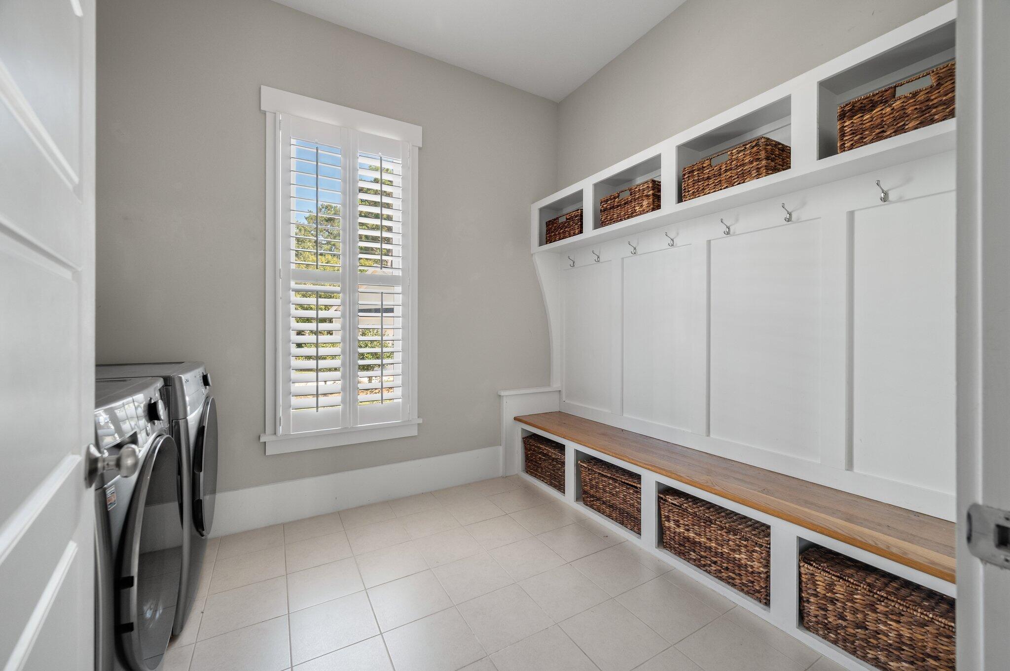Laundry room with washer and dryer, built-in bench, and woven storage baskets.