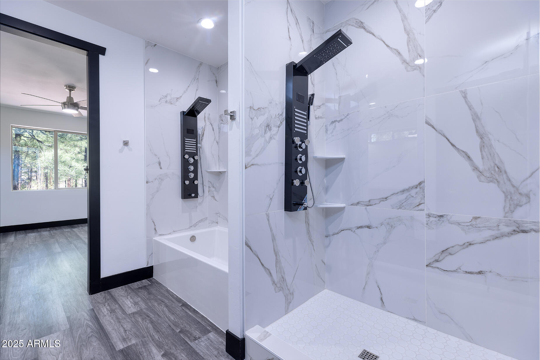 Modern marble-look bathroom with a glass shower, black fixtures, and a white hexagonal tile floor.