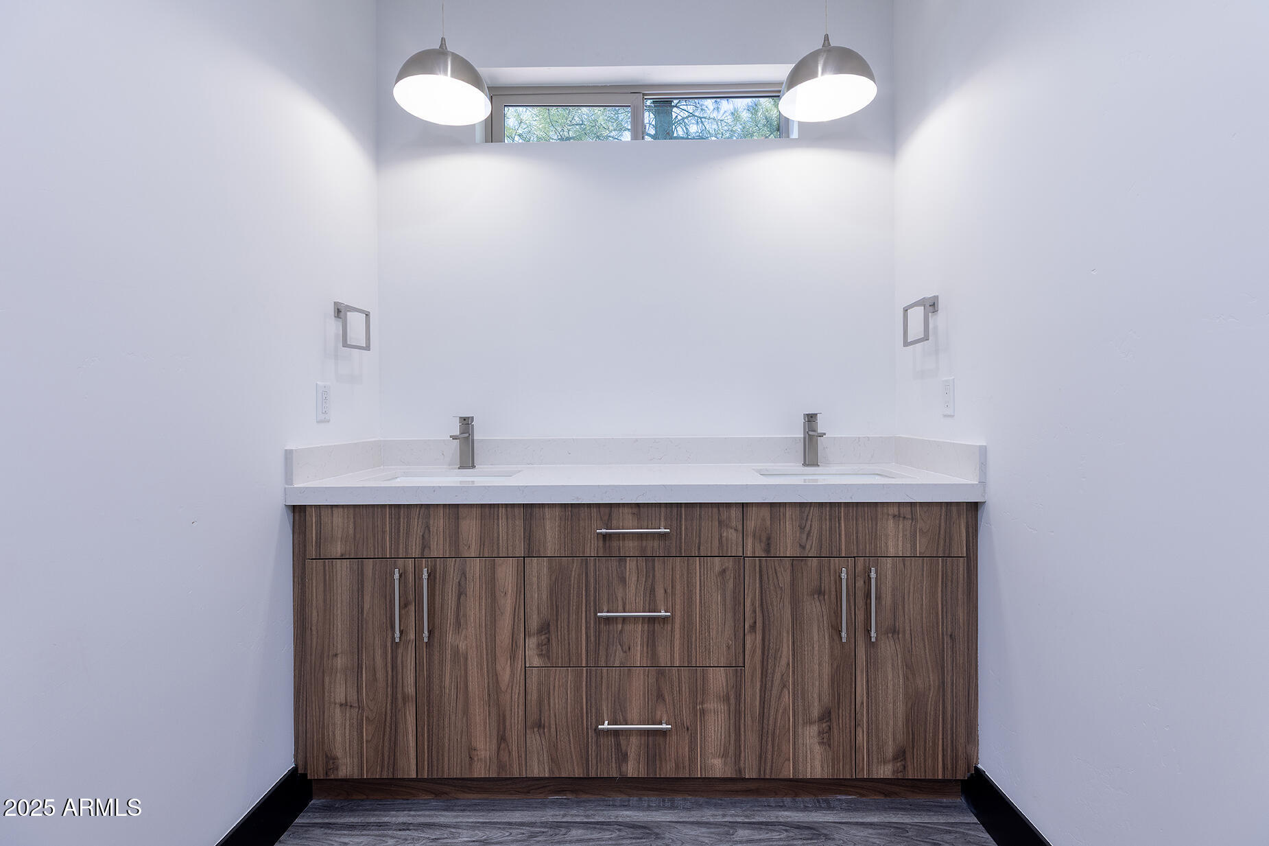 Bathroom vanity with two sinks, a white countertop, and dark wood cabinetry.