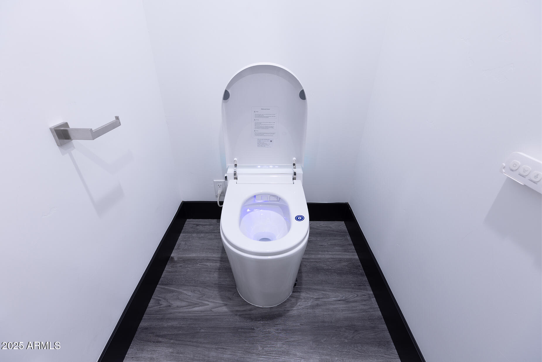 Modern smart toilet with illuminated bidet seat and gray wood-look bathroom flooring.