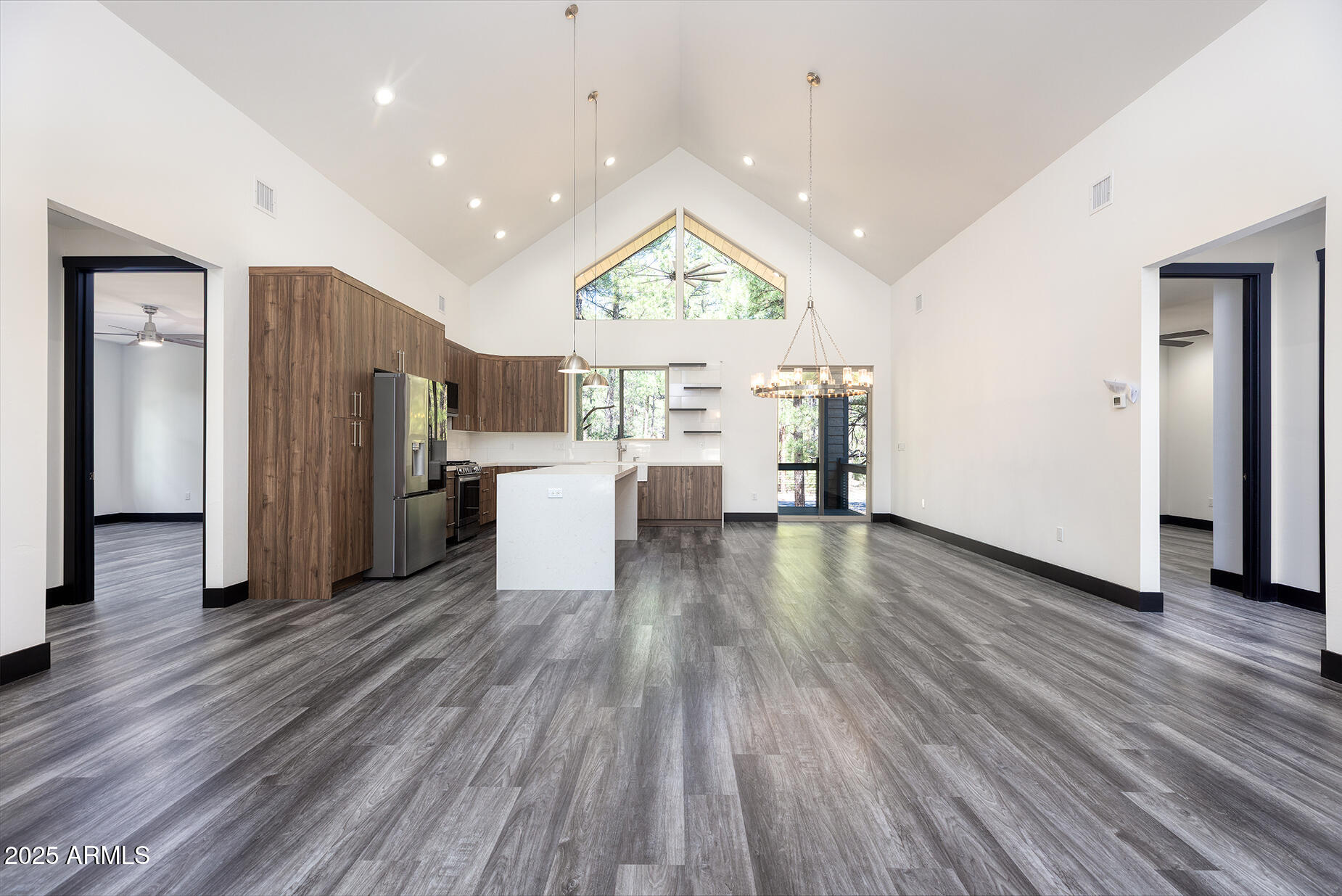 Vacant open-plan kitchen and living area with a vaulted ceiling, white island, and dark wood cabinetry.