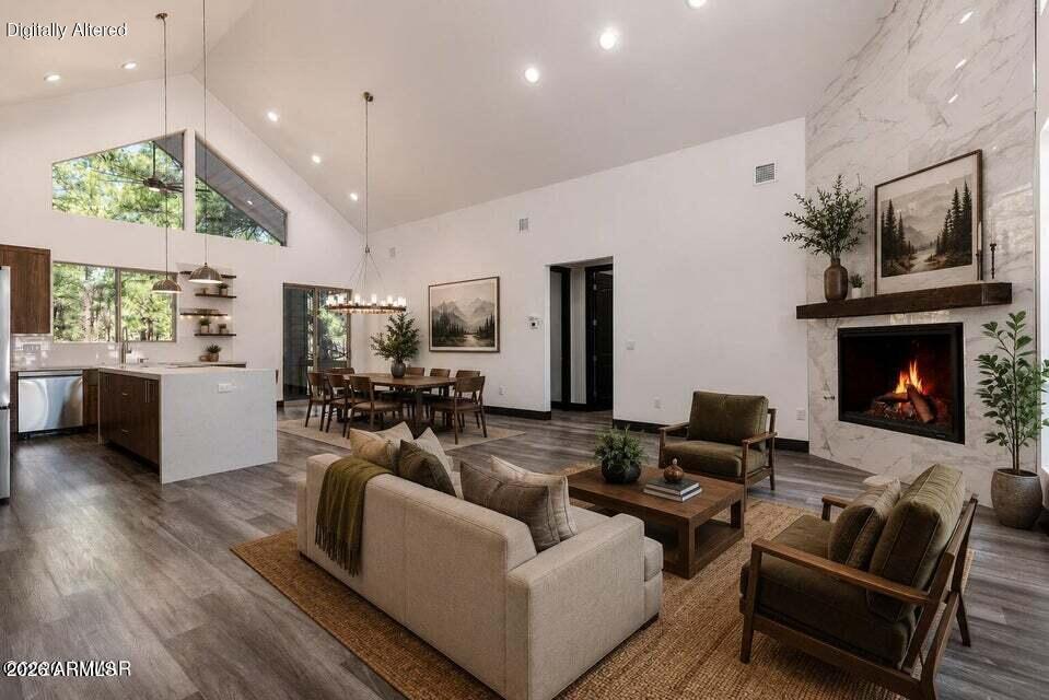 Staged great room with a vaulted ceiling, stone fireplace, and open kitchen and dining area.