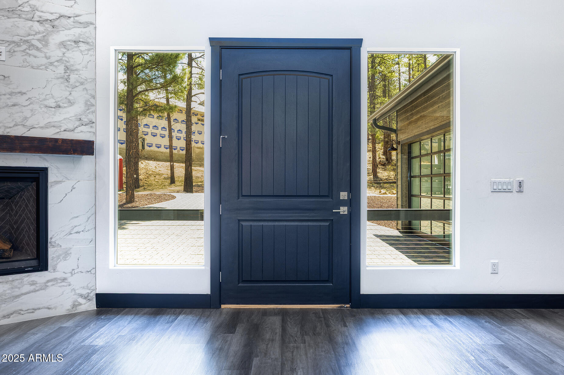 Entryway with a dark blue front door, tall sidelights, marble fireplace, and gray flooring.