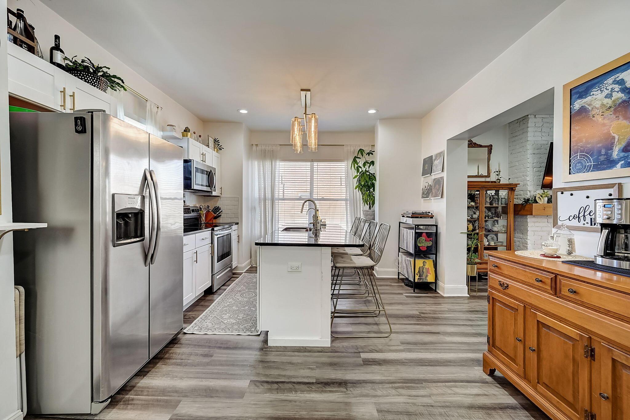 Bright kitchen with a white island, stainless steel appliances, and a wooden coffee bar.
