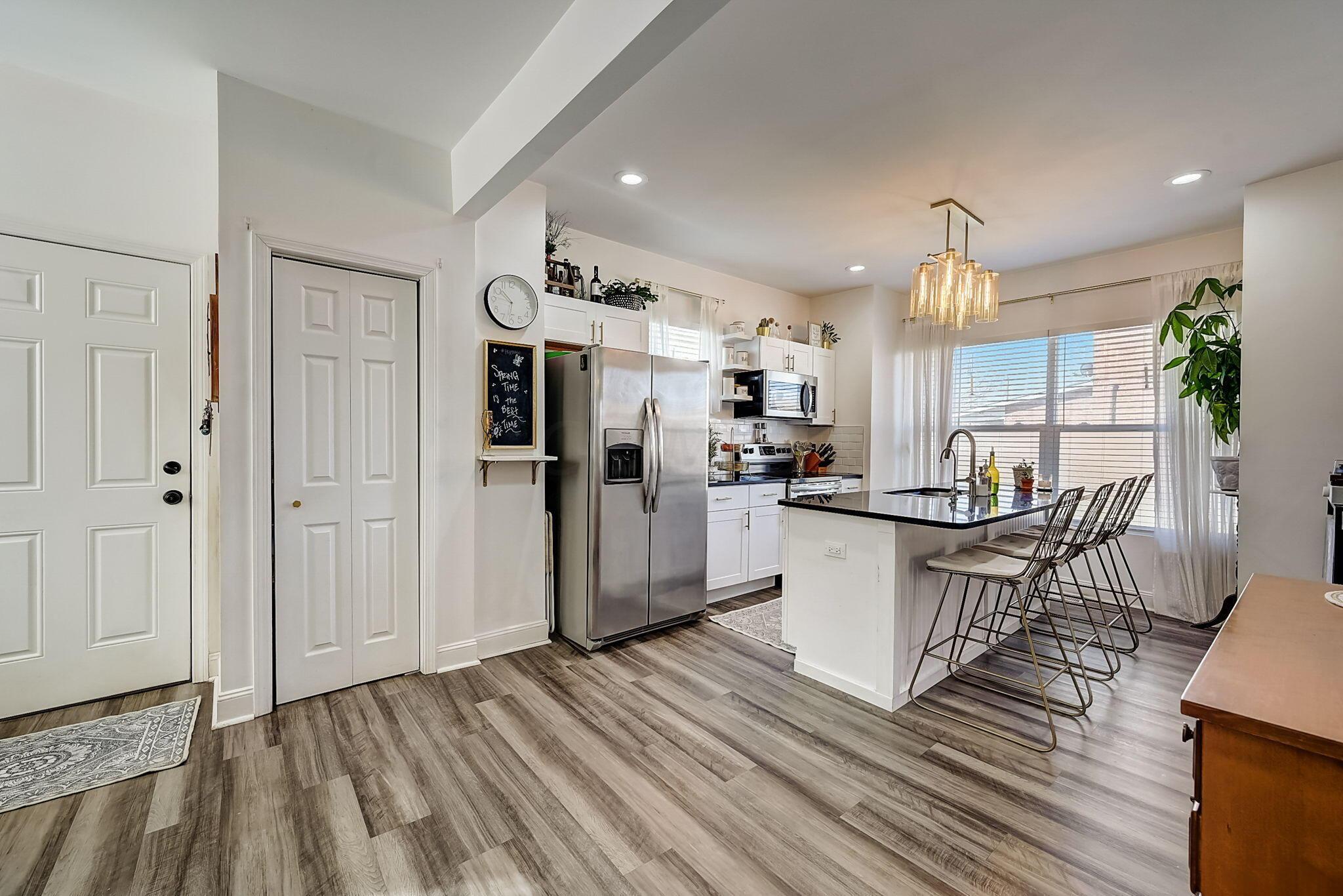 Bright kitchen with stainless appliances, white cabinetry, and a black island lined with bar stools.