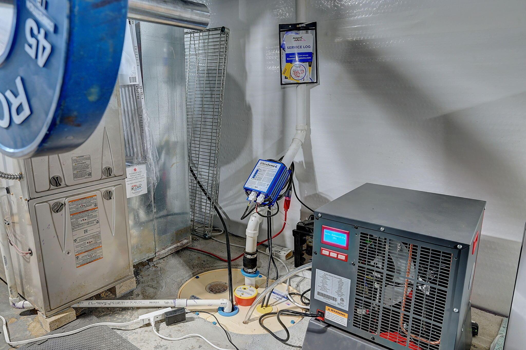 Basement mechanical room with a furnace, sump pump system, and large gray utility unit.