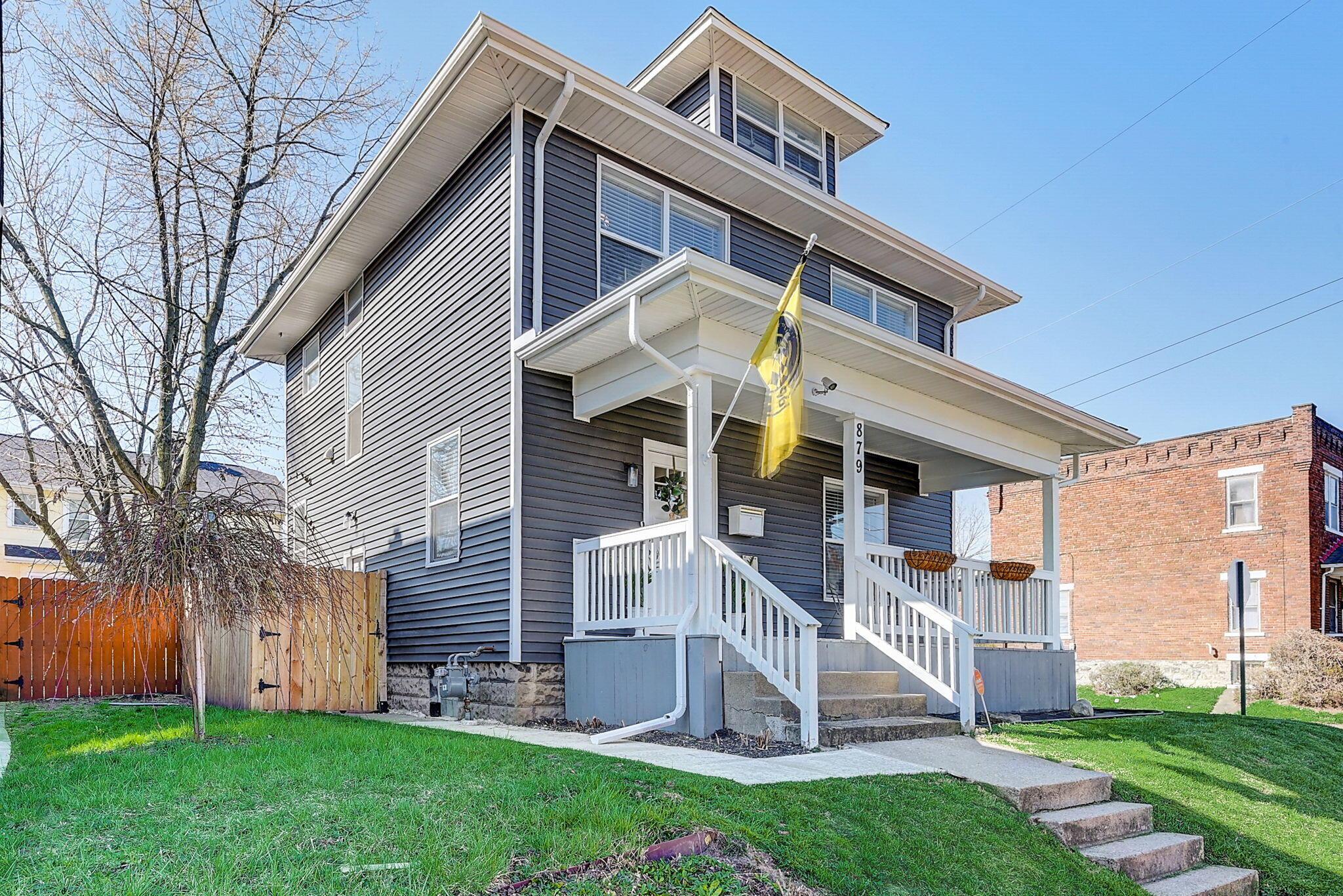 Multi-story dark-sided home with a white-trimmed covered porch and front steps.