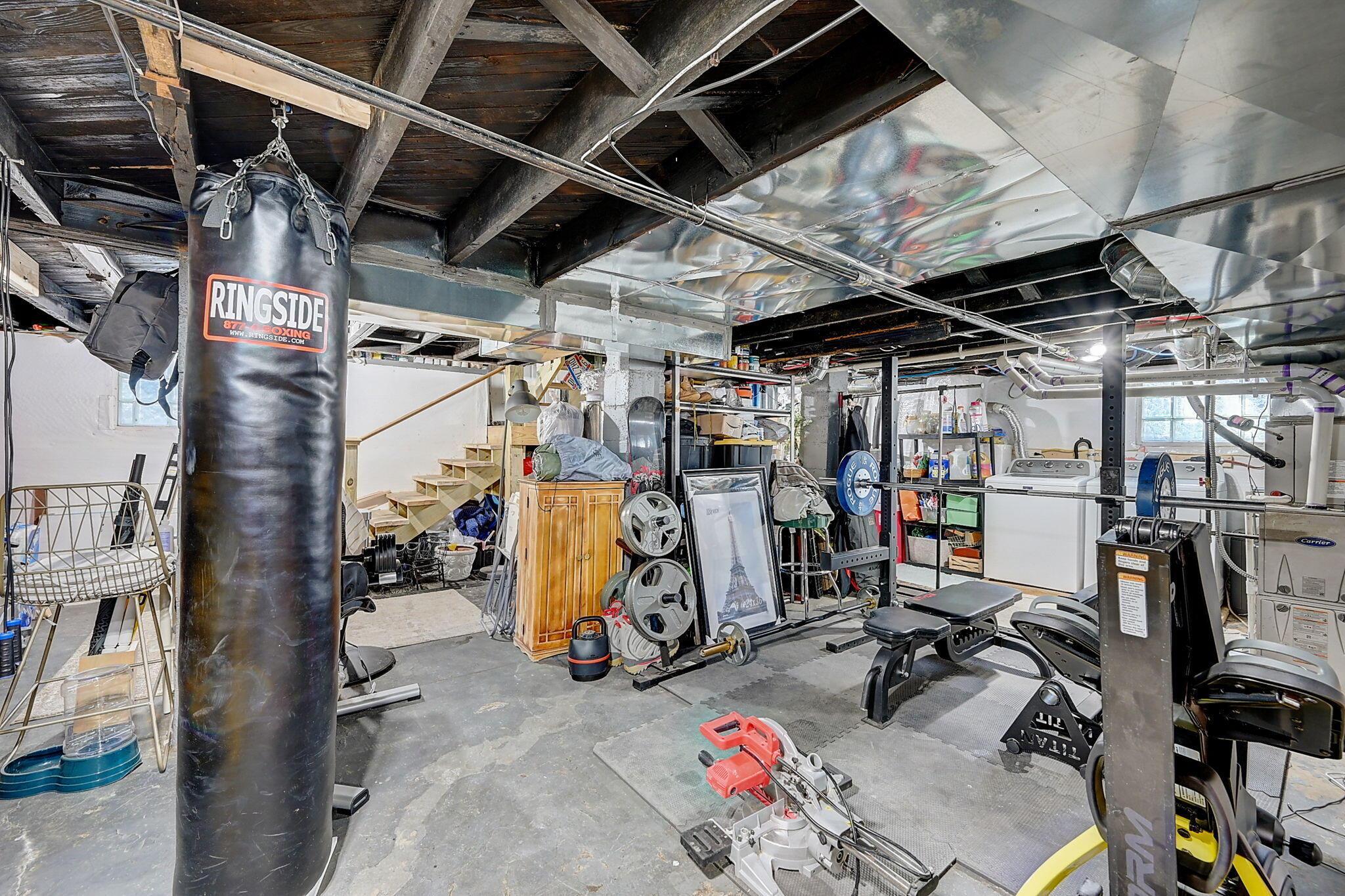 Basement gym with weight machines, free weights, and a hanging punching bag.