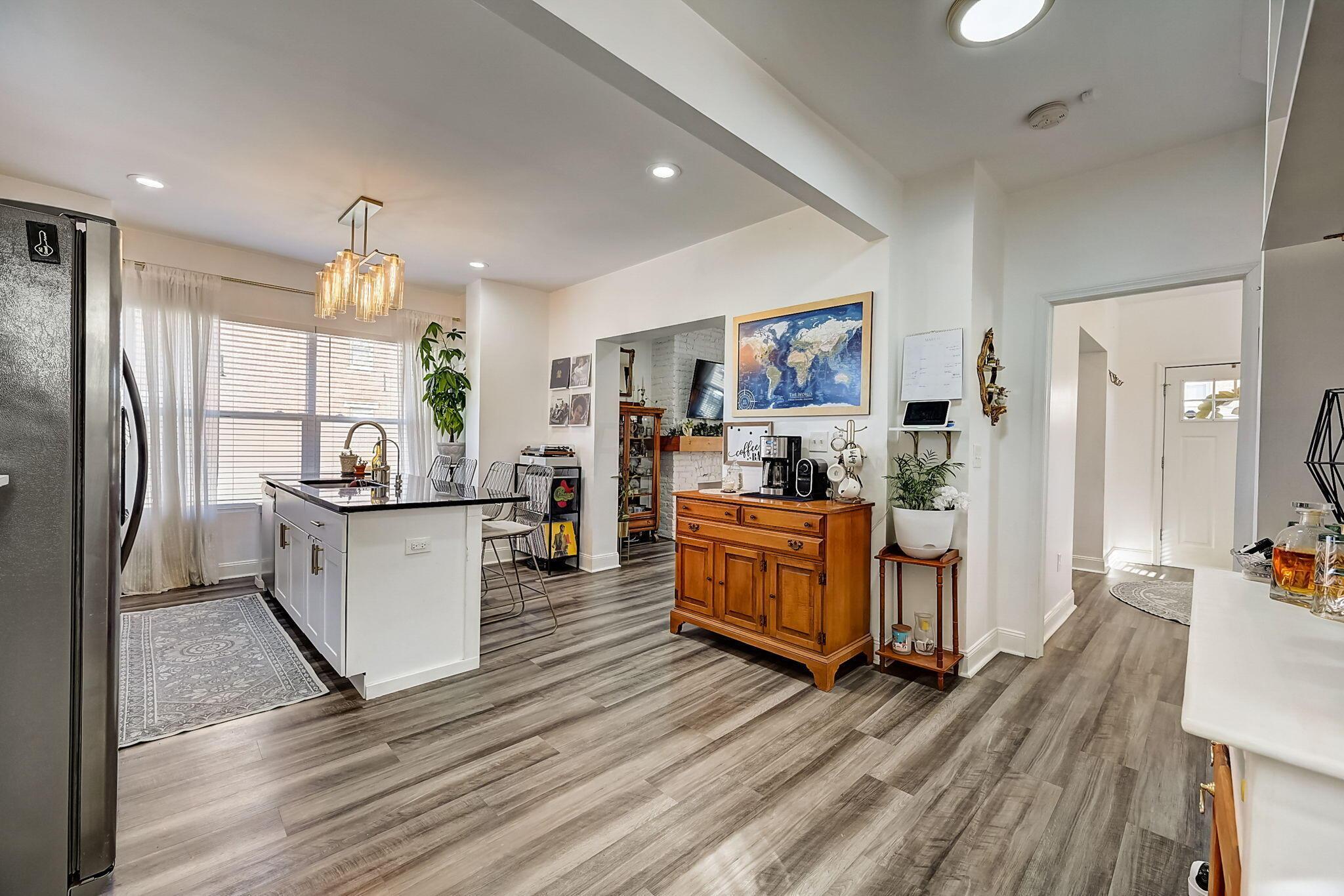 Open kitchen with a white island, stainless-steel refrigerator, and wooden sideboard beneath a world map.