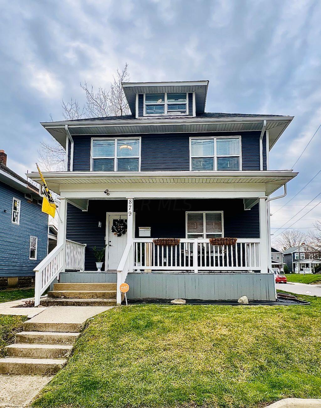 Navy-blue two-story house with white trim, a covered porch, and concrete front steps.