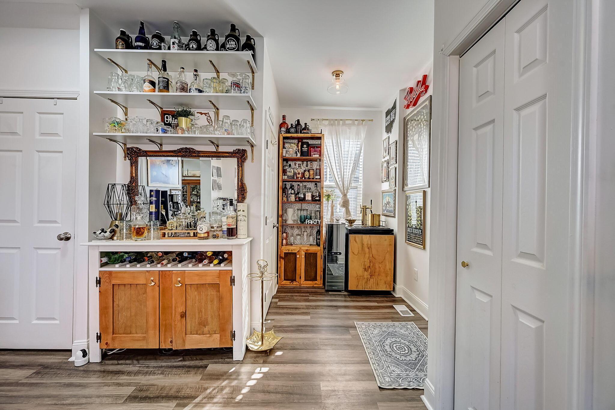 Furnished home bar with bottle-lined shelves, an ornate mirror, and a wooden cabinet.