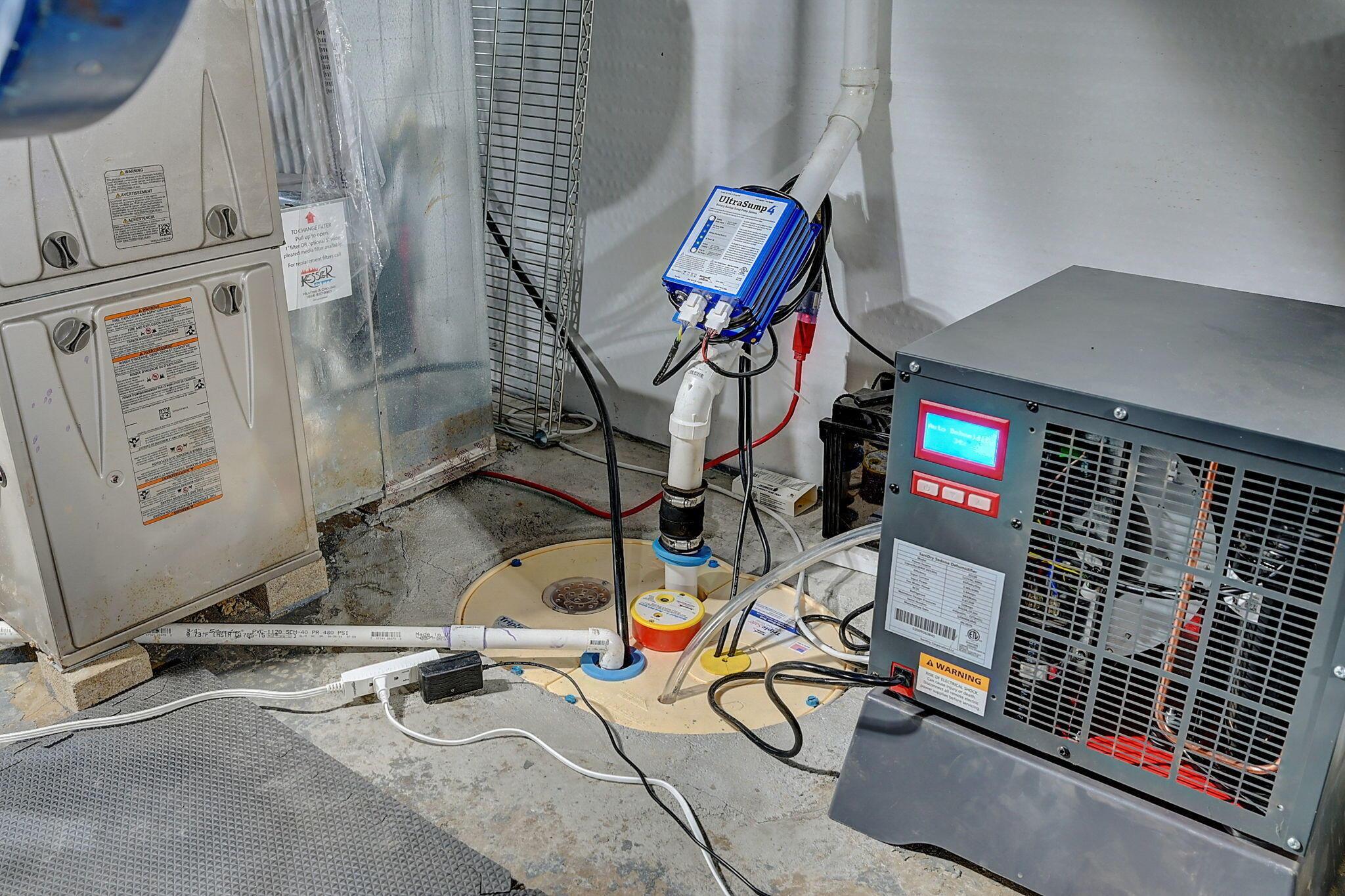 Basement utility equipment with a furnace, sump system, pipes, and gray unit with a display.
