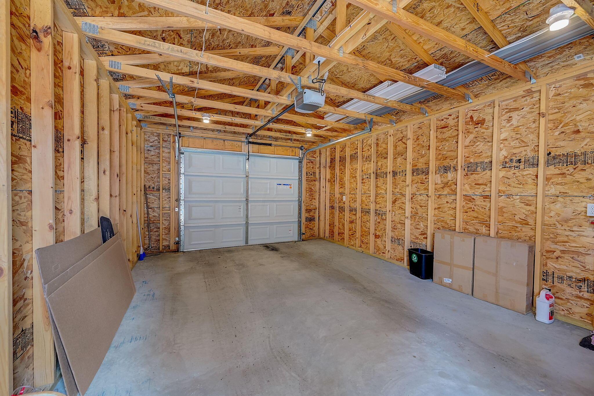 Unfinished garage with exposed framing, a concrete floor, and a closed white garage door.